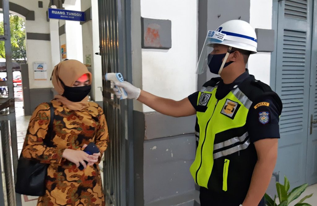 Petugas menggunakan APD mengukur suhu badan pengunjung stasiun. Photo : KAI.id